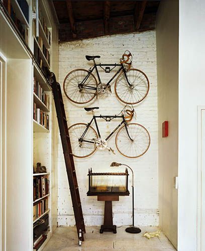 Vélos accrochés au mur et échelle de bibliothèque.